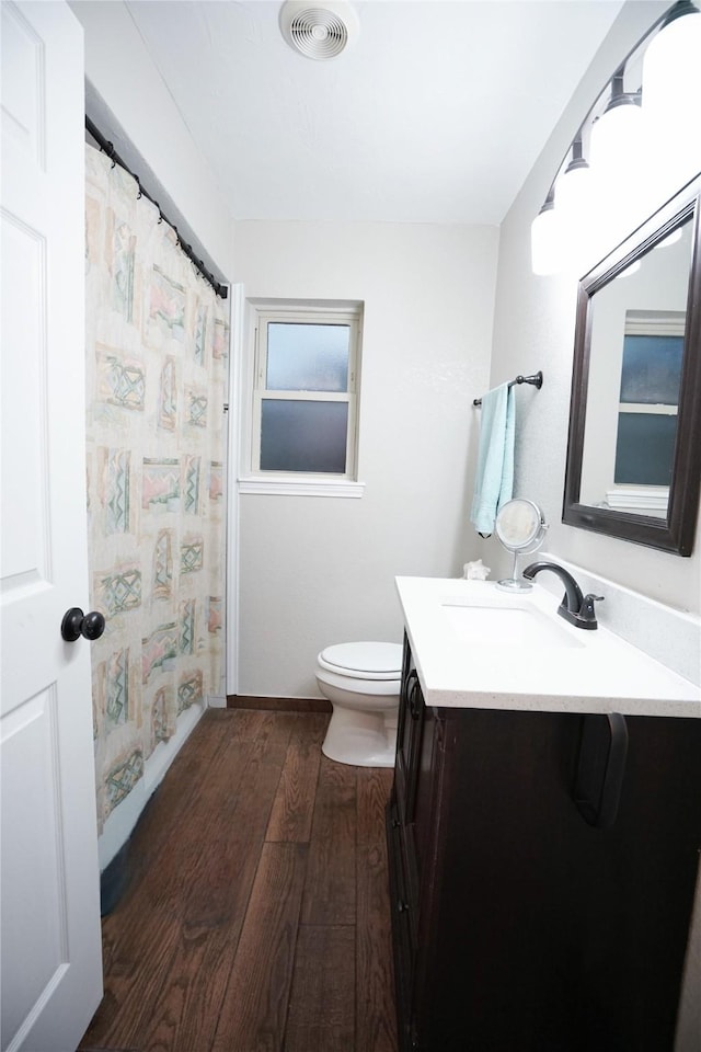 full bathroom with visible vents, a shower with shower curtain, toilet, wood-type flooring, and vanity