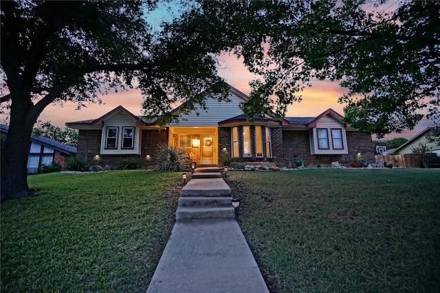 view of front of house featuring brick siding and a lawn