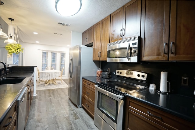 kitchen with visible vents, dark countertops, wood finished floors, stainless steel appliances, and a sink