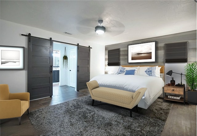 bedroom with ceiling fan, a barn door, wood finished floors, and visible vents