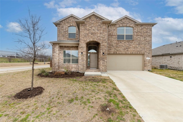 traditional-style house with a garage, central AC unit, concrete driveway, and brick siding