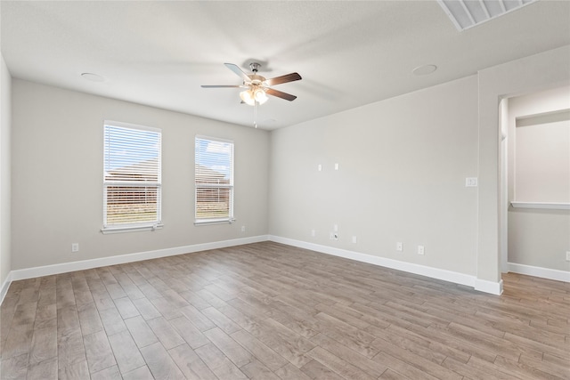 unfurnished room featuring visible vents, wood finished floors, a ceiling fan, and baseboards