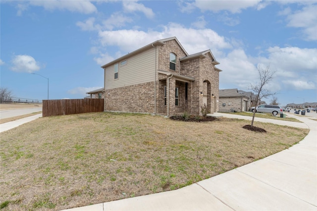 view of home's exterior with brick siding, a lawn, an attached garage, fence, and driveway