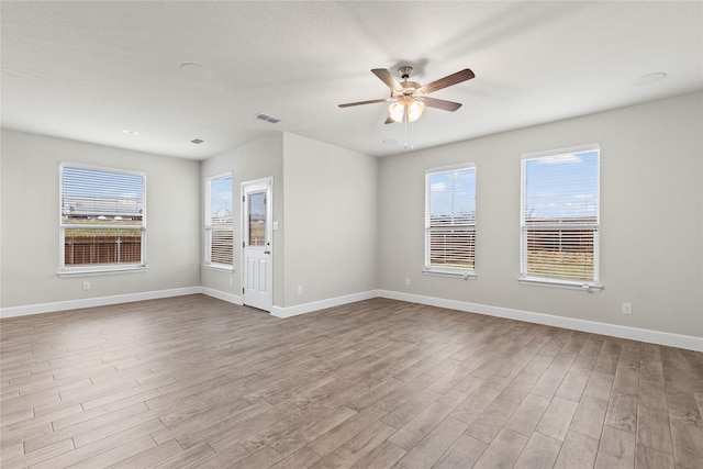 empty room with a ceiling fan, baseboards, visible vents, and wood finished floors