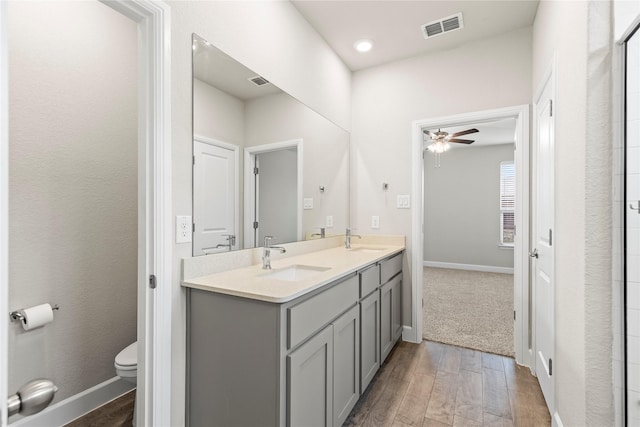 bathroom with toilet, wood finished floors, a sink, and visible vents