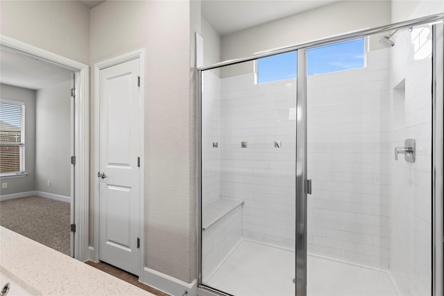 bathroom featuring a stall shower, a wealth of natural light, and baseboards