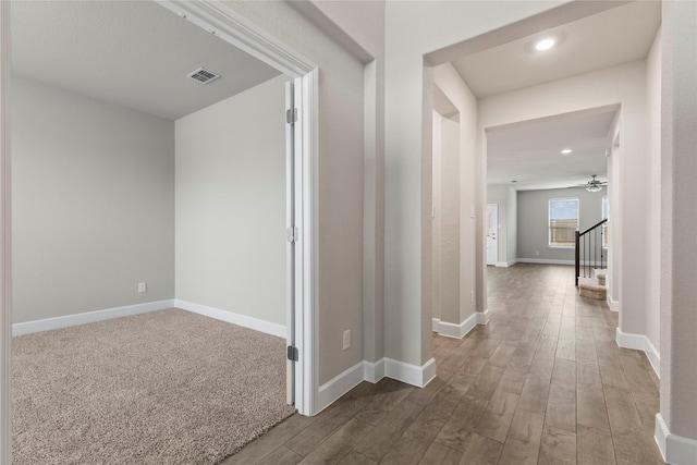 hall featuring stairway, wood finished floors, visible vents, and baseboards