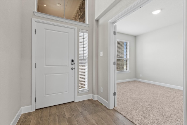 carpeted entrance foyer with wood finished floors and baseboards