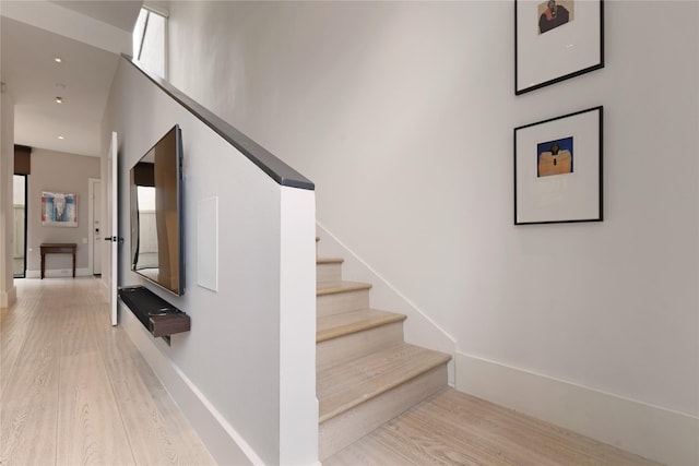 staircase featuring baseboards and wood finished floors