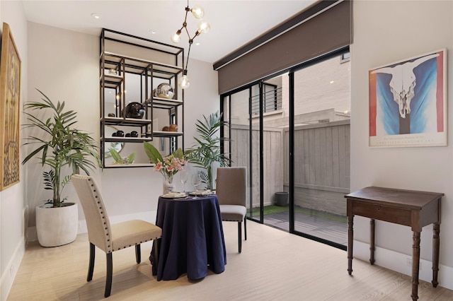 dining area featuring a chandelier, baseboards, and wood finished floors