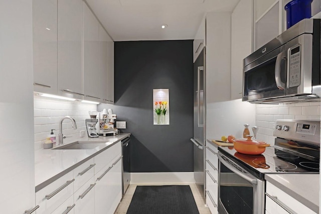 kitchen featuring stainless steel appliances, light countertops, a sink, and modern cabinets