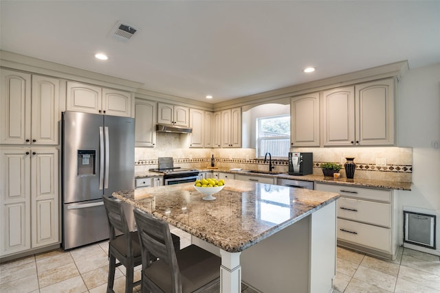 kitchen with light stone counters, appliances with stainless steel finishes, a sink, and visible vents