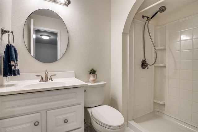 full bathroom featuring toilet, a textured wall, a shower, and vanity