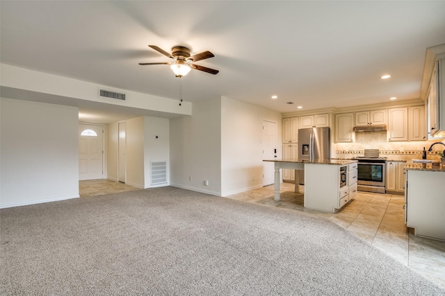 kitchen with under cabinet range hood, light carpet, a kitchen island, a sink, and appliances with stainless steel finishes