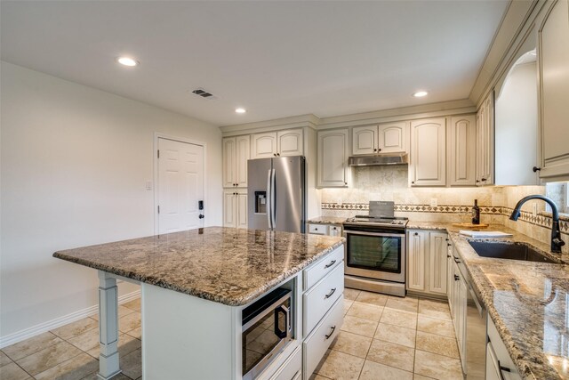 kitchen featuring stone counters, stainless steel appliances, a sink, visible vents, and tasteful backsplash