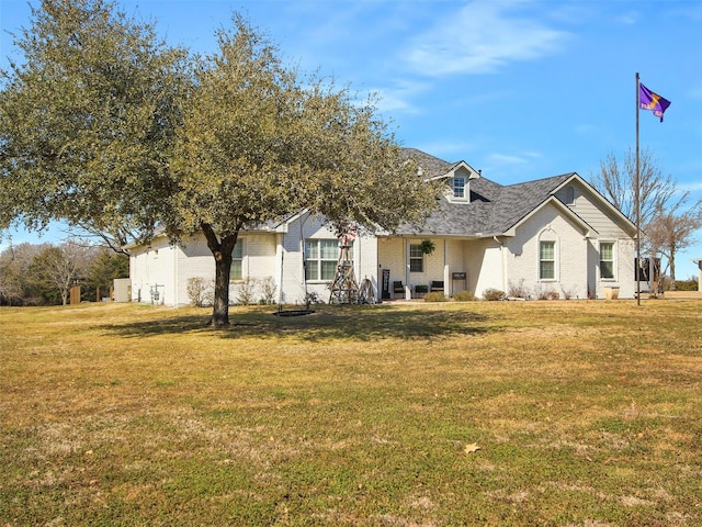 view of front of property with a shingled roof, brick siding, and a front lawn