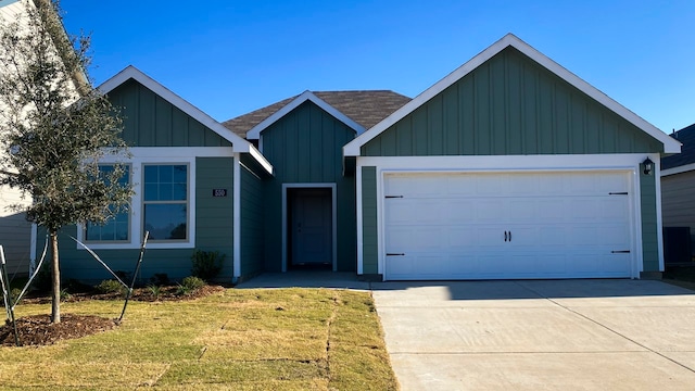 ranch-style house with an attached garage, concrete driveway, roof with shingles, a front lawn, and board and batten siding