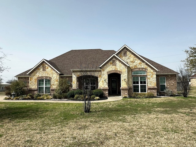 view of front facade featuring a front yard, brick siding, and roof with shingles