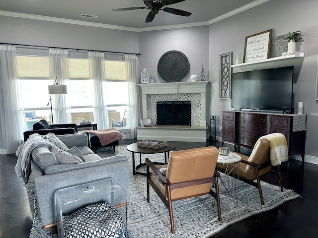 living area featuring baseboards, visible vents, a ceiling fan, a tiled fireplace, and ornamental molding