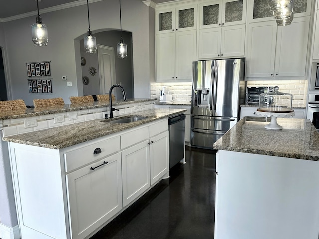 kitchen with stainless steel appliances, a sink, a kitchen island with sink, and decorative backsplash