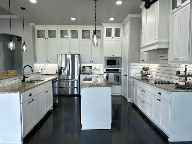 kitchen featuring an island with sink, appliances with stainless steel finishes, glass insert cabinets, and a sink