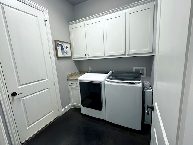 clothes washing area featuring washing machine and clothes dryer, cabinet space, and baseboards