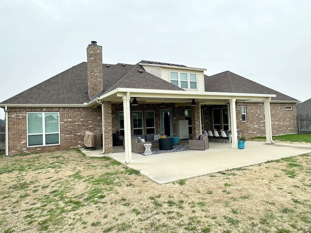 back of house with brick siding, a patio, and an outdoor living space