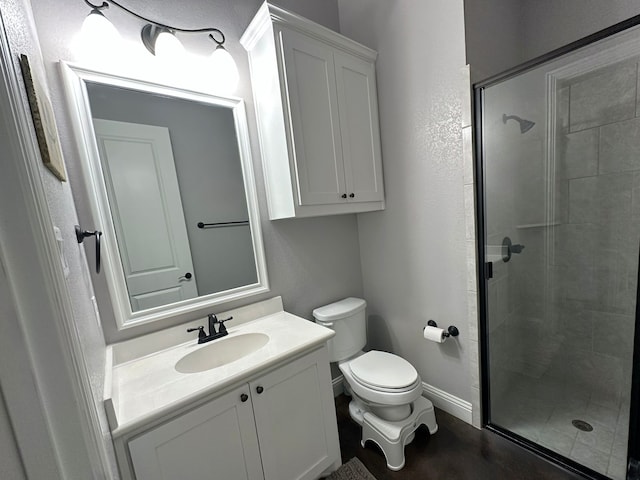 bathroom with baseboards, a shower stall, toilet, and vanity