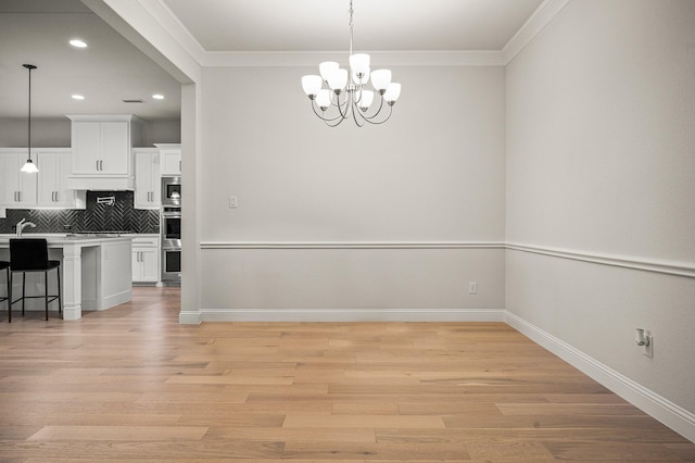 dining space with light wood-type flooring, crown molding, baseboards, and a notable chandelier