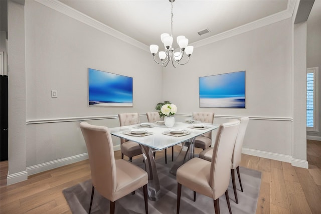 dining area with an inviting chandelier, visible vents, ornamental molding, and wood finished floors