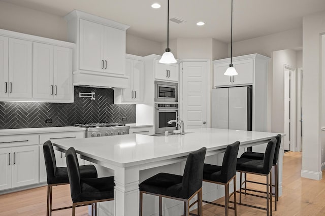 kitchen featuring custom exhaust hood, stainless steel appliances, tasteful backsplash, visible vents, and light wood-style floors