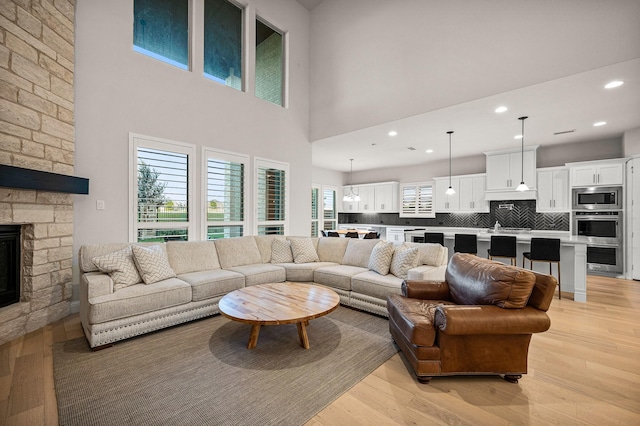 living room featuring a high ceiling, a fireplace, light wood-style flooring, and recessed lighting