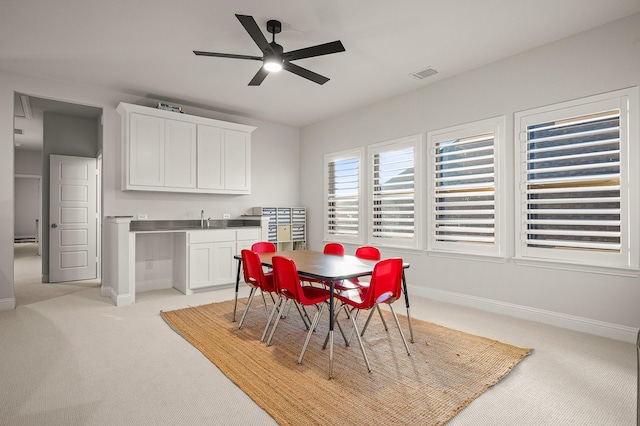 dining space with light colored carpet, visible vents, ceiling fan, and baseboards