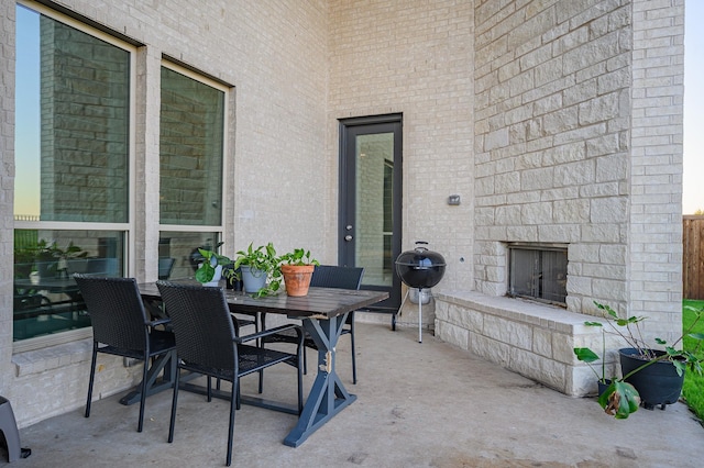 view of patio with outdoor dining area, an outdoor stone fireplace, and grilling area