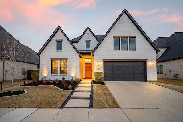 view of front of home featuring metal roof, a garage, brick siding, concrete driveway, and a standing seam roof