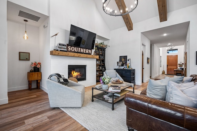 living room featuring high vaulted ceiling, a fireplace, wood finished floors, and visible vents