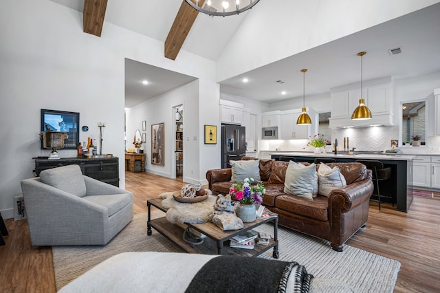 living room featuring high vaulted ceiling, light wood-style floors, visible vents, and beamed ceiling