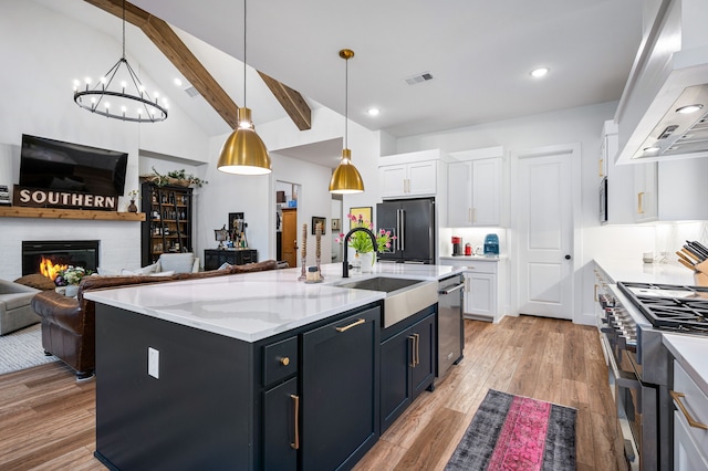 kitchen with premium appliances, visible vents, white cabinetry, wall chimney range hood, and beamed ceiling