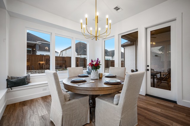 dining area featuring an inviting chandelier, baseboards, visible vents, and wood finished floors