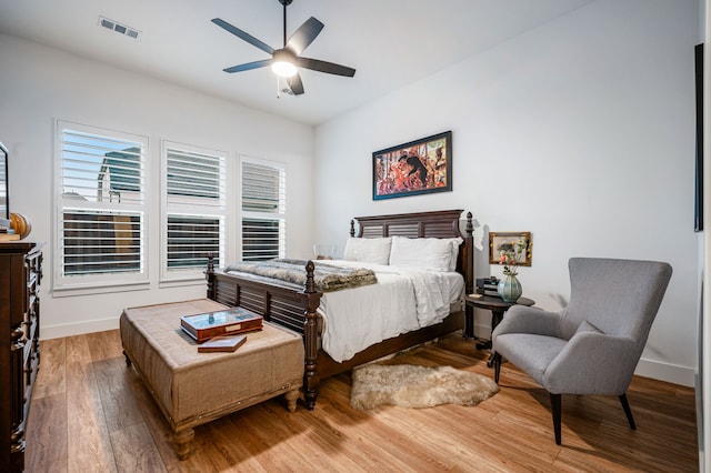 bedroom with a ceiling fan, baseboards, visible vents, and hardwood / wood-style floors