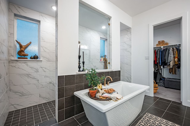 full bath with a spacious closet, a soaking tub, tile walls, and a walk in shower