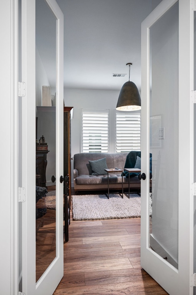 hallway with french doors, visible vents, and wood finished floors