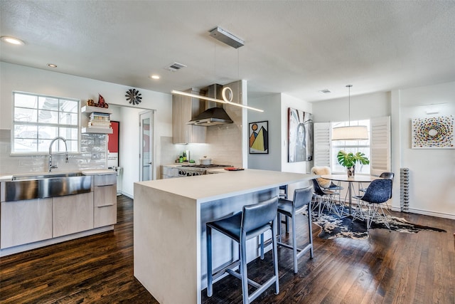 kitchen with visible vents, wall chimney range hood, light countertops, dark wood-style floors, and modern cabinets