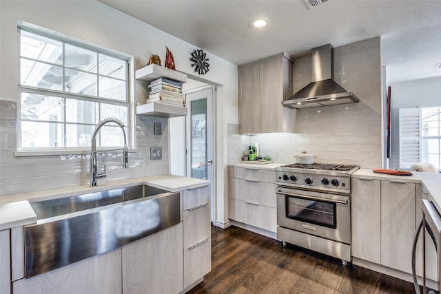 kitchen featuring dark wood-style flooring, stainless steel range, light countertops, wall chimney range hood, and modern cabinets