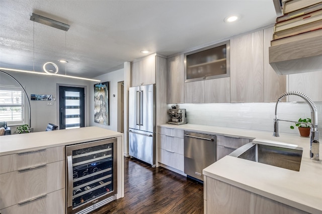 kitchen with beverage cooler, light countertops, appliances with stainless steel finishes, modern cabinets, and a sink