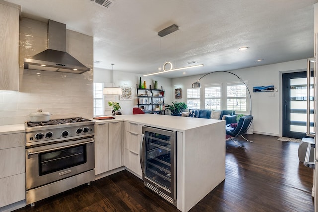 kitchen with wall chimney range hood, beverage cooler, open floor plan, a peninsula, and high end stainless steel range oven