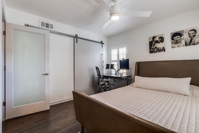 bedroom with a barn door, visible vents, dark wood finished floors, and a ceiling fan