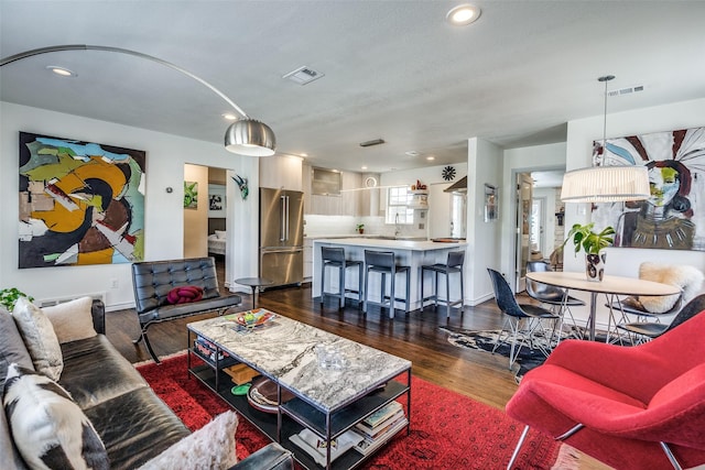 living room featuring dark wood-style floors, visible vents, and recessed lighting