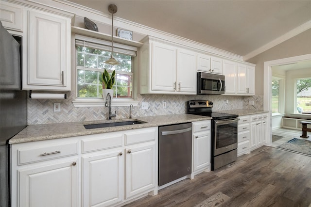 kitchen with tasteful backsplash, white cabinets, appliances with stainless steel finishes, vaulted ceiling, and a sink