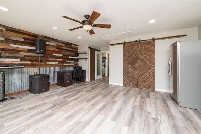 unfurnished office featuring recessed lighting, wood finished floors, wooden walls, and a barn door